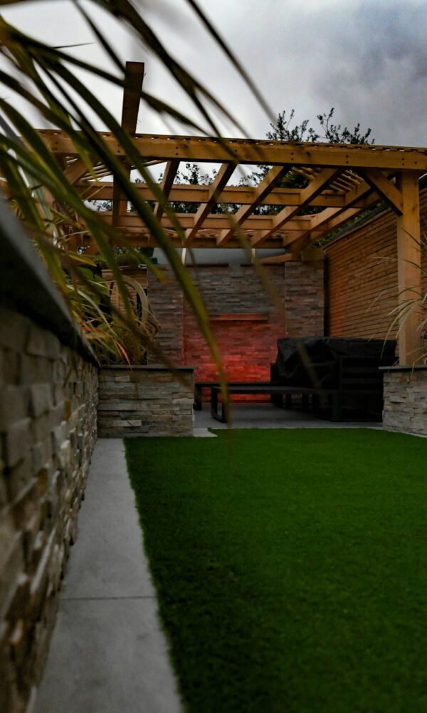 a backyard with a green lawn and a stone wall