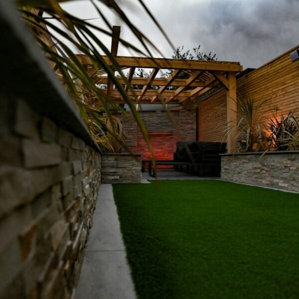 a backyard with a green lawn and a stone wall