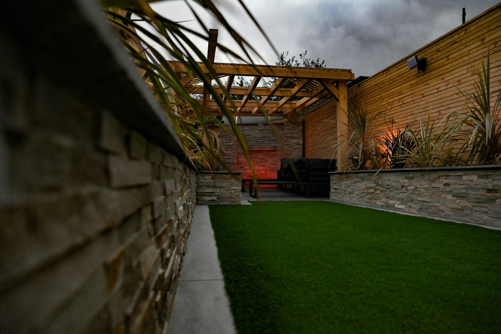 a backyard with a green lawn and a stone wall