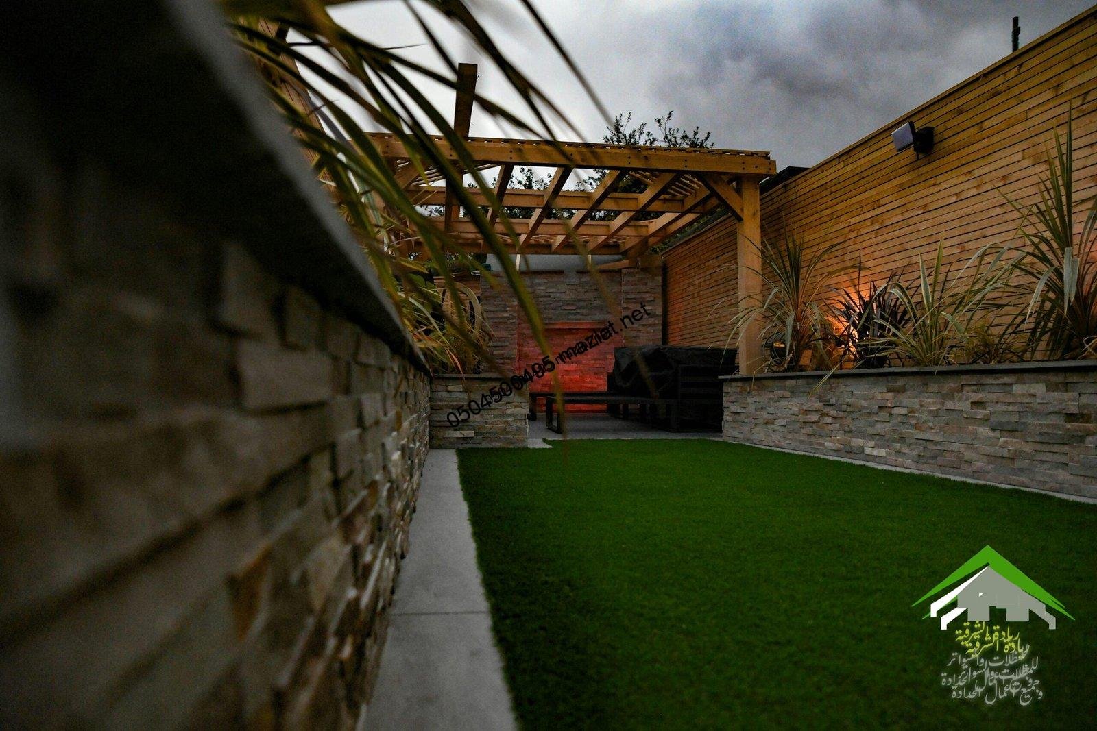 a backyard with a green lawn and a stone wall